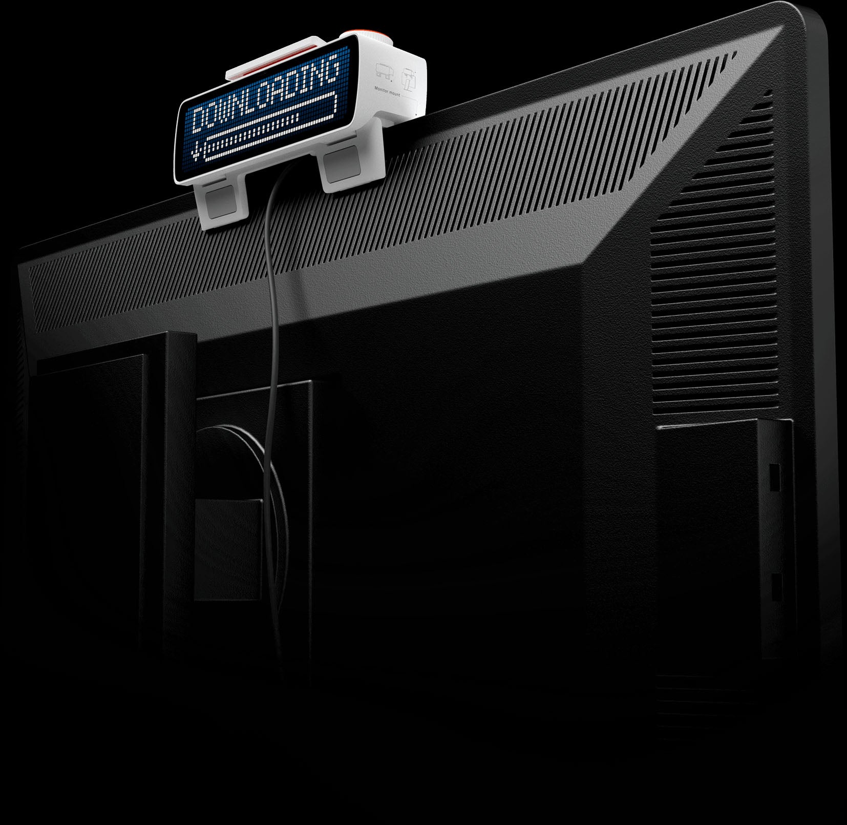Back of a monitor with a small white device clipped on top showing a pixelated progress bar labeled 'DOWNLOADING'.